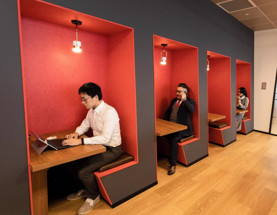 Professionals working privately in modern booth-style coworking spaces.
